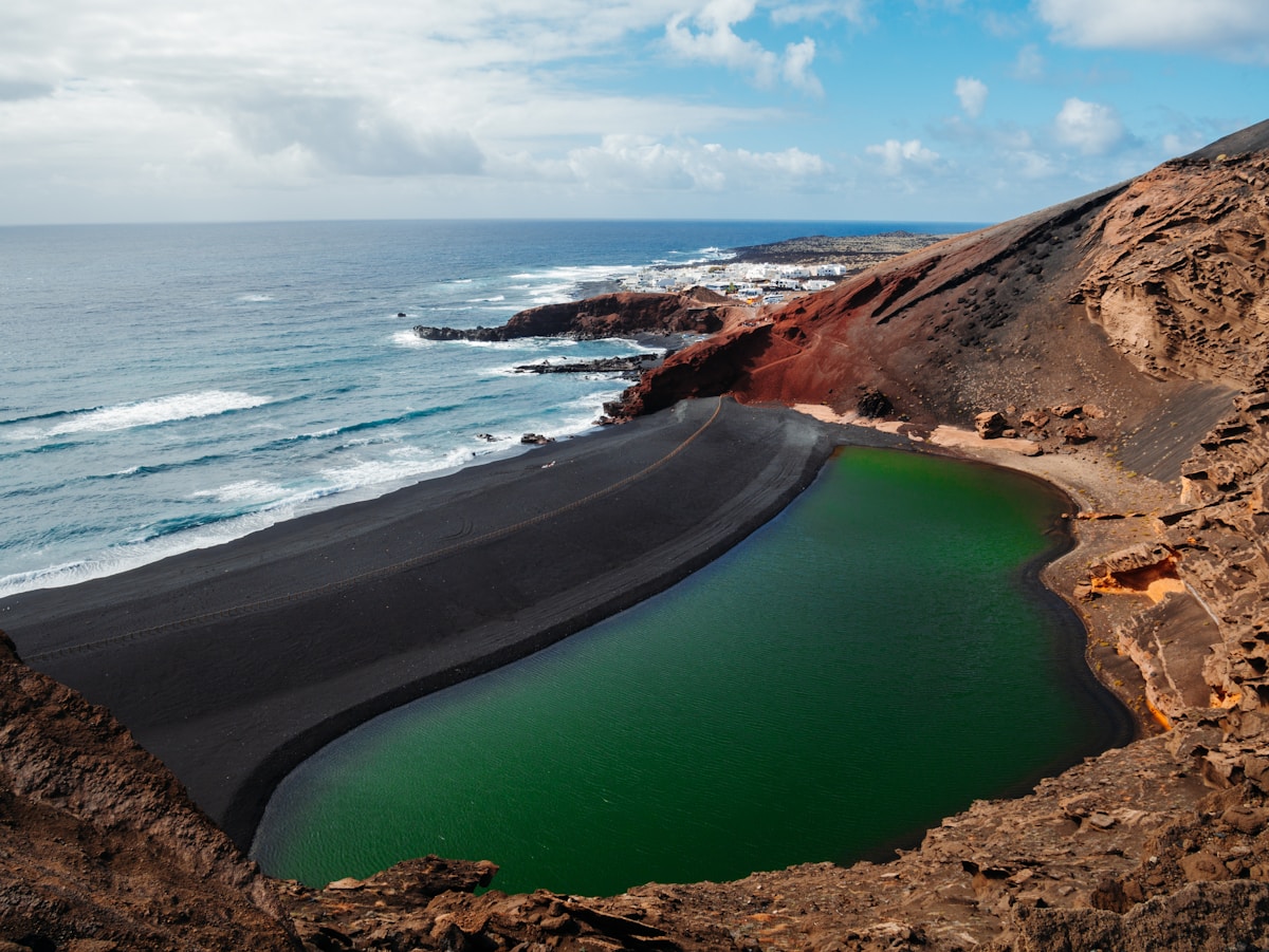 Laguna verde y playa de arena volcánica junto al mar en Lanzarote